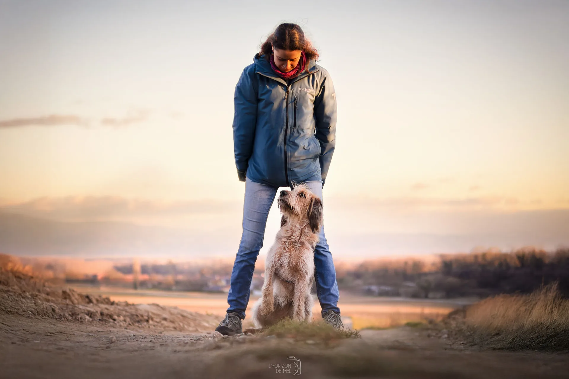 Julie et son chien socca dans les champs au couché du soleil