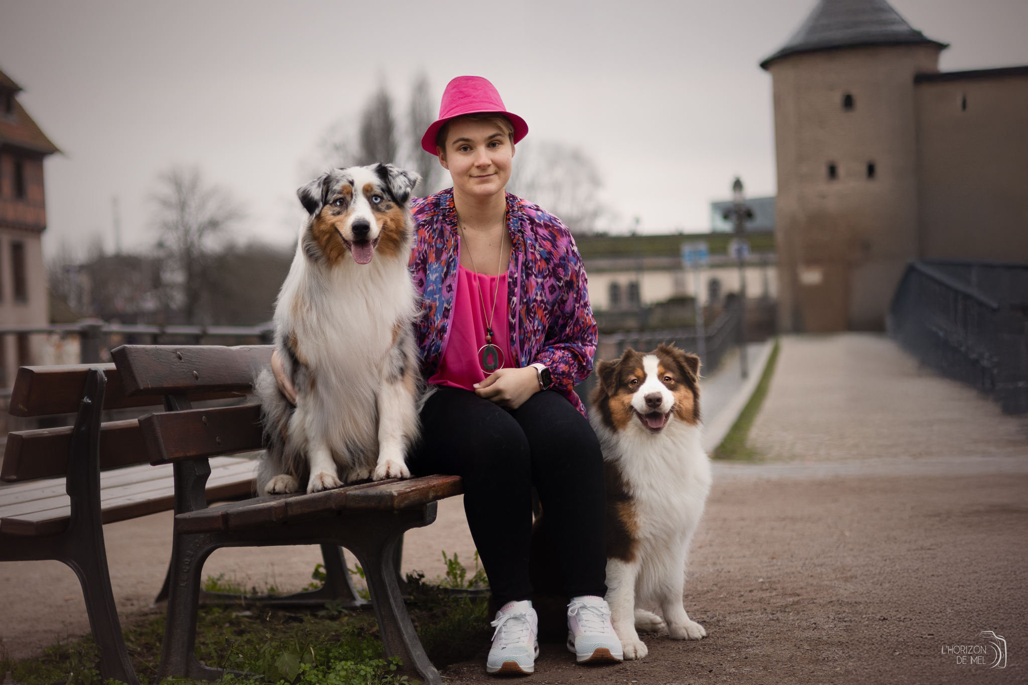 Une jeune fille et ses deux chiens en ville près d'un banc