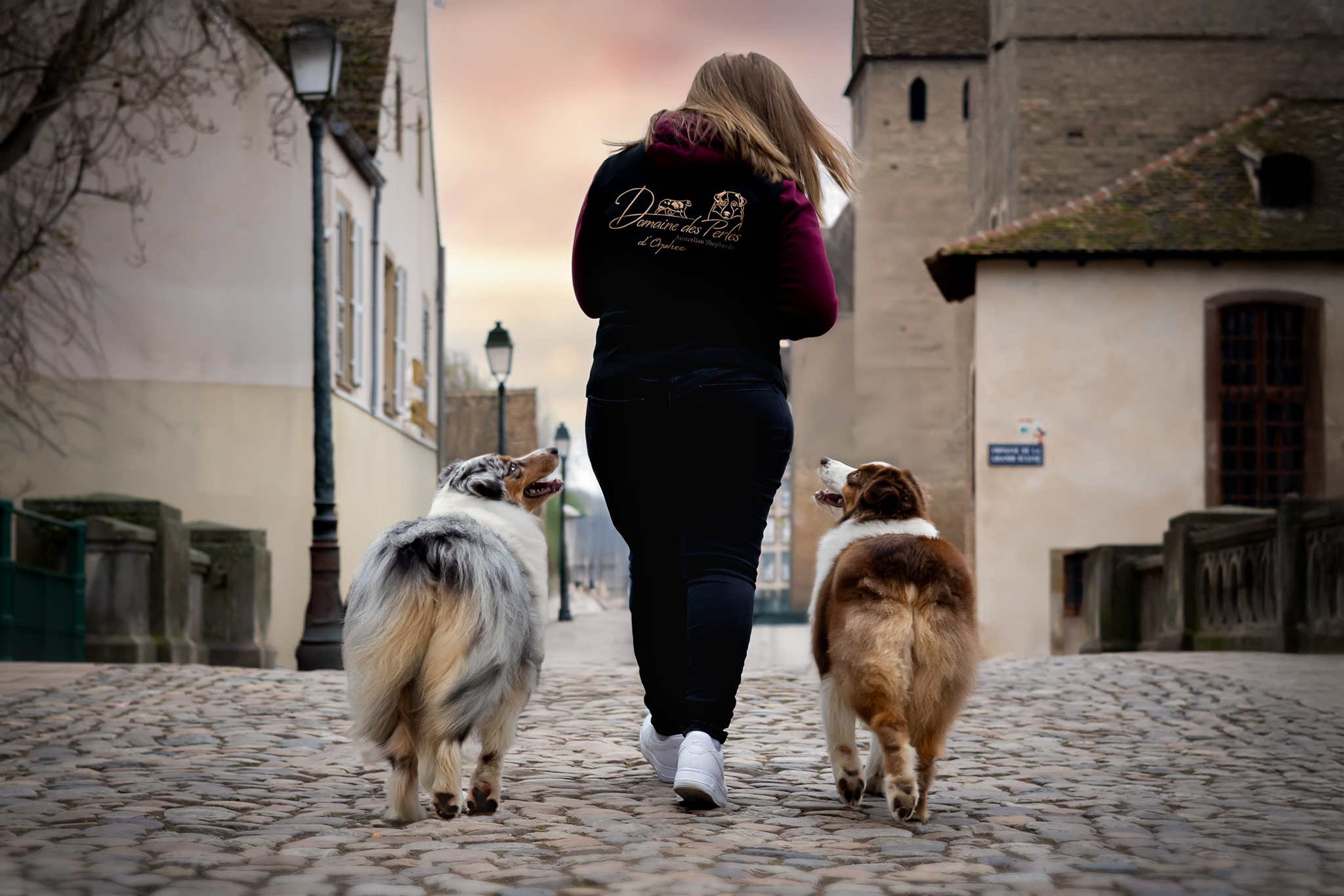 Mélanie de dos avec ses deux chiens qui marchent dans les rues de strasbourg